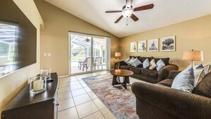 A living room with a ceiling fan, a sofa set, a coffee table, a lamp, and a sliding glass door leading to an outdoor area. - 638 - Beautiful Pool Villa Highlands Reserve Newly Modernised 4 Bed Property (Davenport)