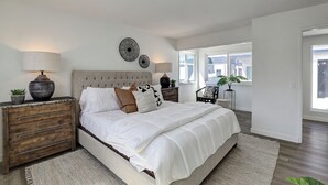 Une chambre avec un grand lit, des tables de chevet en bois et une vue sur l’extérieur.