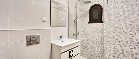 A modern bathroom with a glass-enclosed shower, a white vanity with a mirror, and a tiled backsplash.