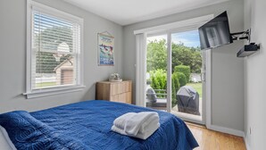 Ein Schlafzimmer mit einem großen Bett, einem an der Wand montierten Fernseher und einer Glastür zum Patio.