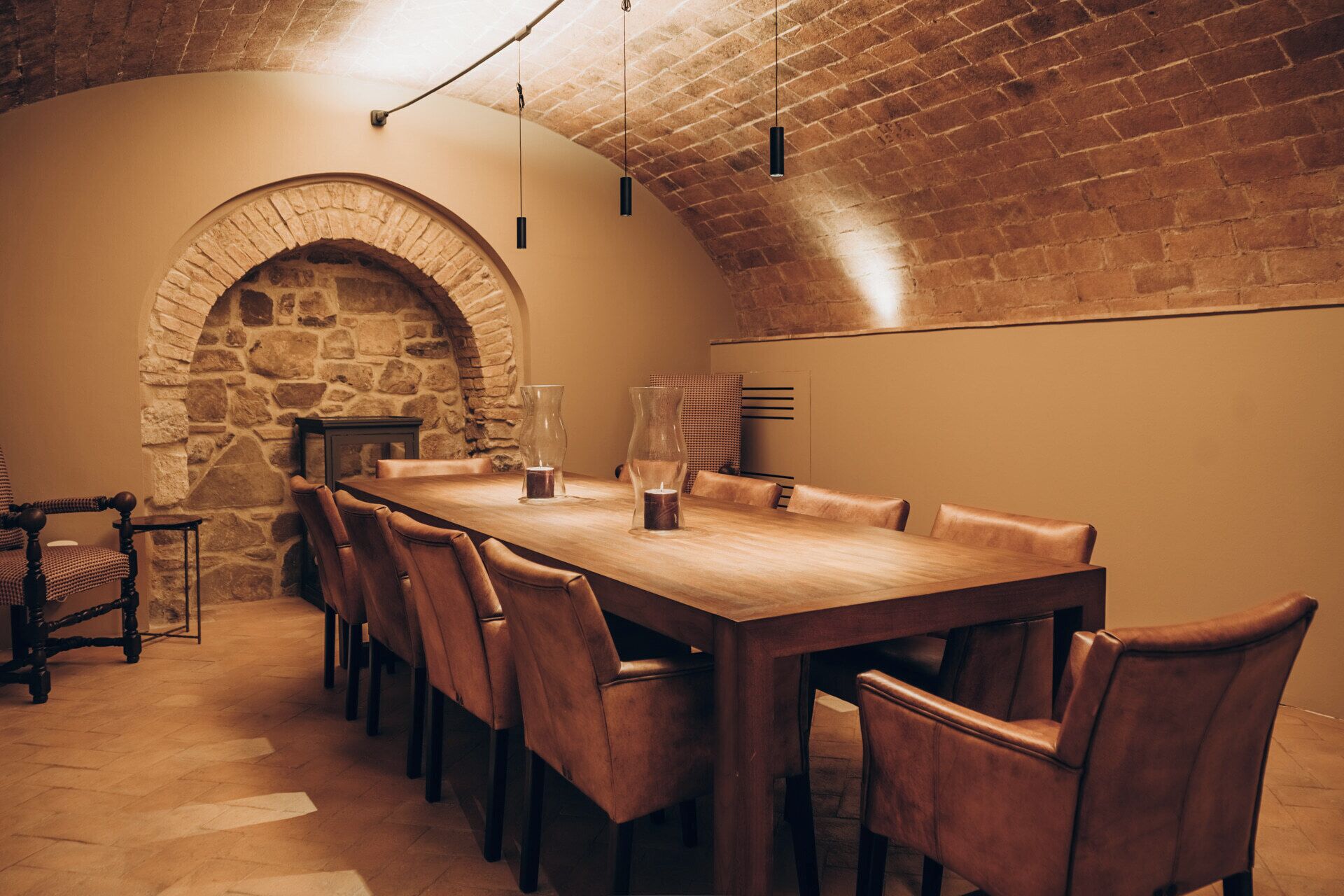 A dining area with a long wooden table, leather chairs, and a stone archway.