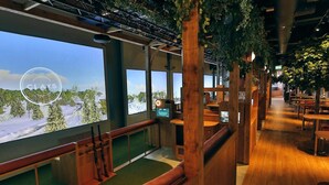 Un restaurante con interiores de madera, ventanas amplias y vistas a un paisaje nevado.