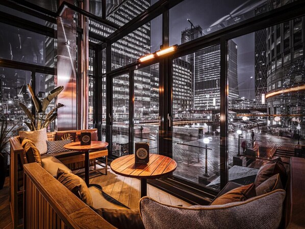 A modern interior with a large window overlooking a cityscape at night.