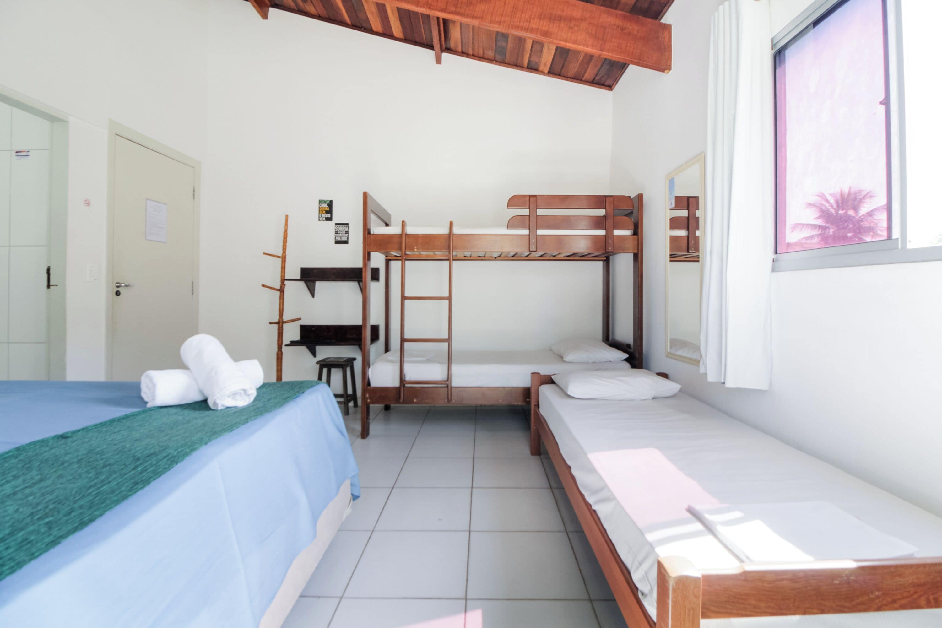 A room with bunk beds, a desk, and a window with curtains.
