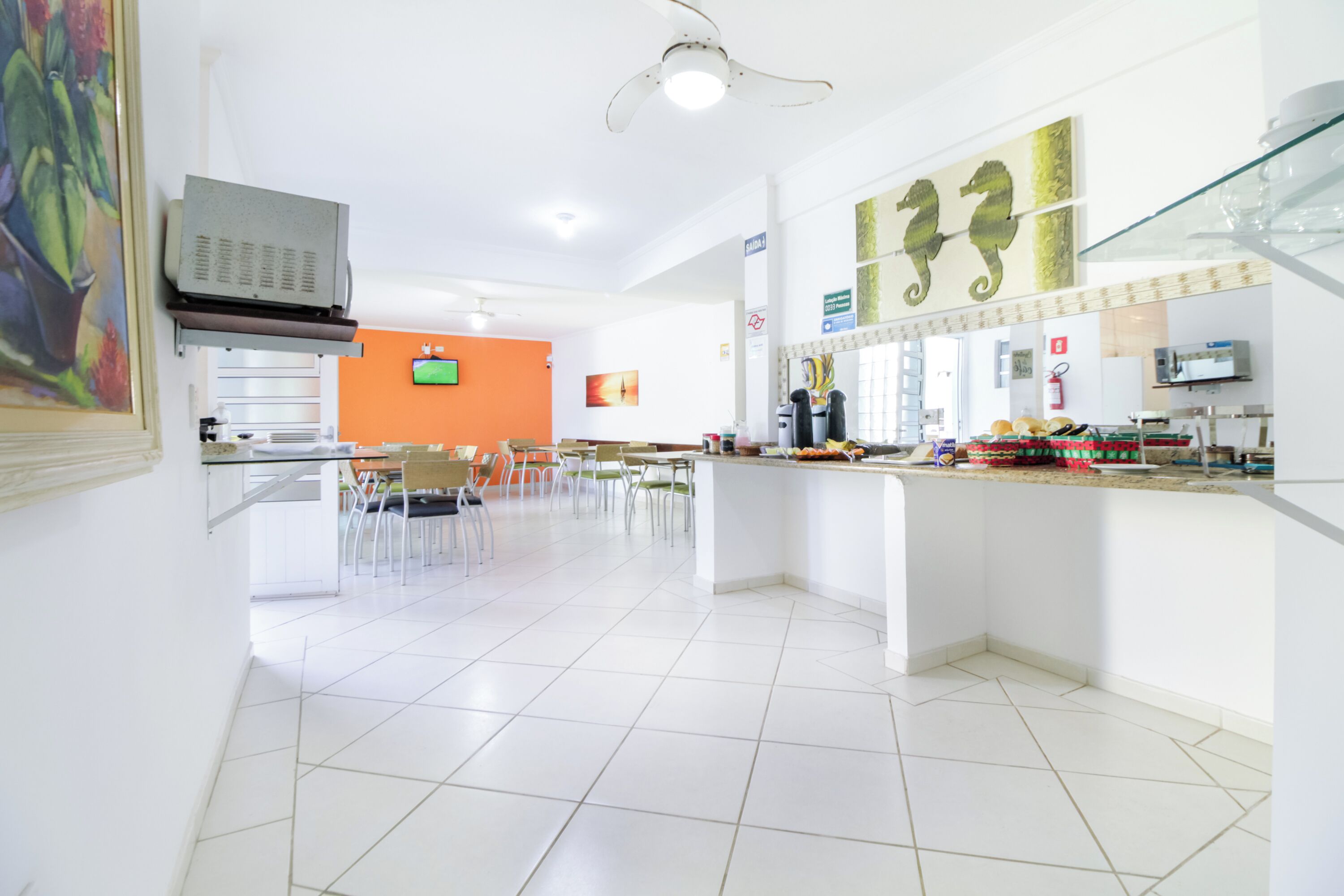 A modern kitchen with white tiles, a central island, and a seating area with chairs.