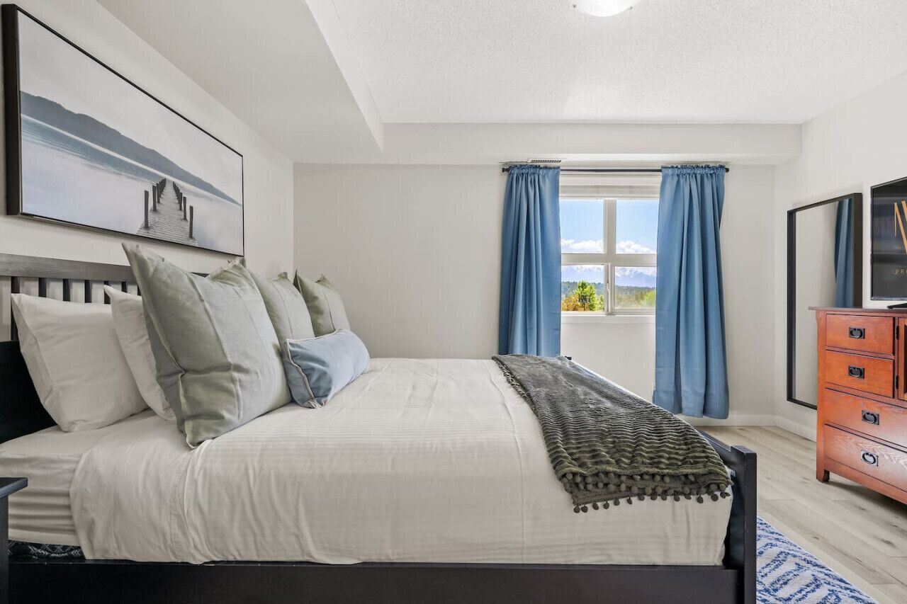 Une chambre à coucher avec un lit, une commode et une fenêtre avec des rideaux.