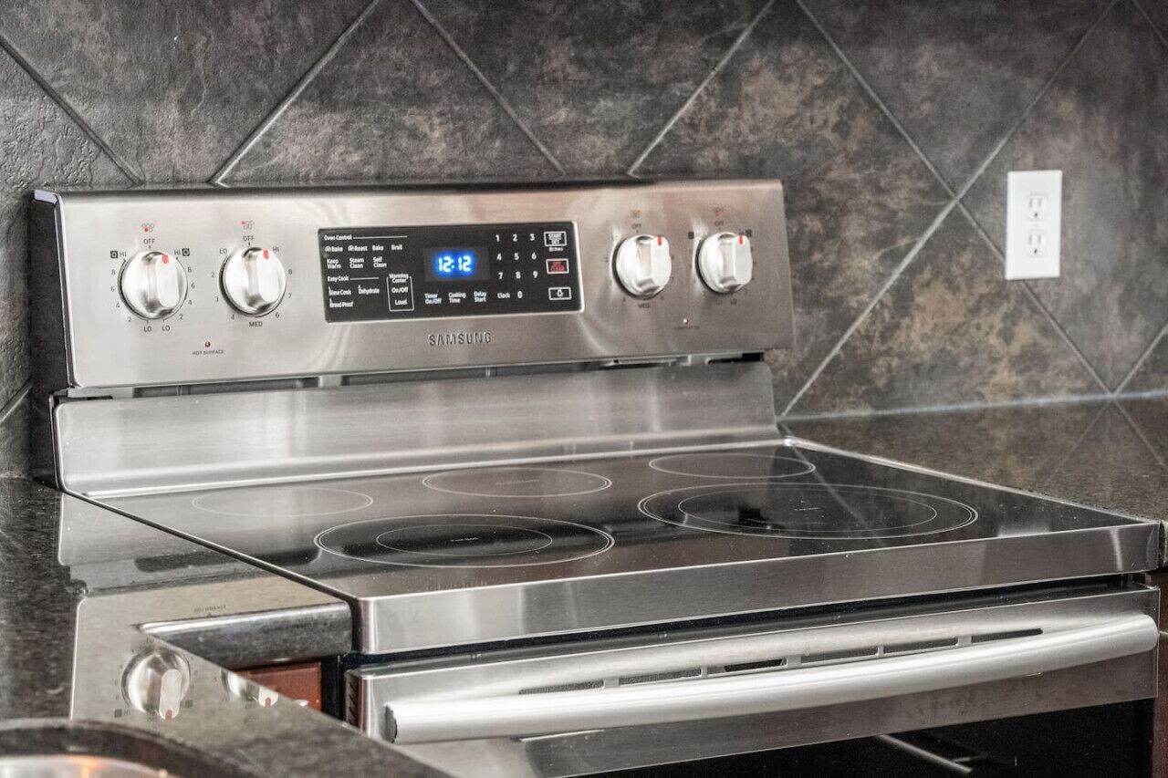 Une cuisinière à gaz Samsung en acier inoxydable, dotée de quatre brûleurs et d’un panneau de commande numérique.