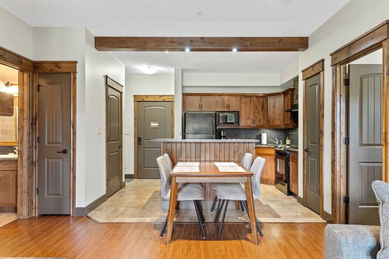 Une cuisine moderne avec des meubles en bois, un îlot central et un coin repas comprenant une table et des chaises.