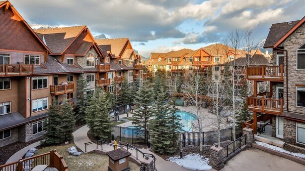 Un hotel de varios pisos con un patio central que cuenta con una piscina, rodeado de árboles y un suelo cubierto de nieve.