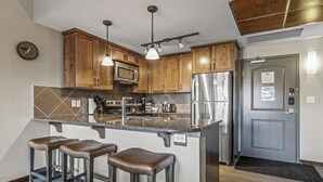 Una cocina con armarios de madera, electrodomésticos de acero inoxidable y una barra con taburetes.