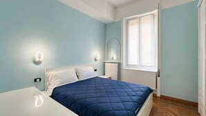 A bedroom with a bed, a nightstand, a mirror, and a window. - Center Apartment - Affitti Brevi Italia (Lecco)