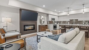 A modern living room with a fireplace, a television, and a kitchen area with bar stools. - 3 bed/2 bath Sparrowhawk Resort-Topfloor-Sleeps 8 (Dead Man's Flats)
