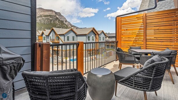 A balcony with wicker furniture, a table, and a view of houses and a mountain. - 3 bed/2 bath Sparrowhawk Resort-Topfloor-Sleeps 8 (Dead Man's Flats)
