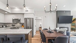 A modern kitchen with white cabinets, stainless steel appliances, and a central island with bar stools.