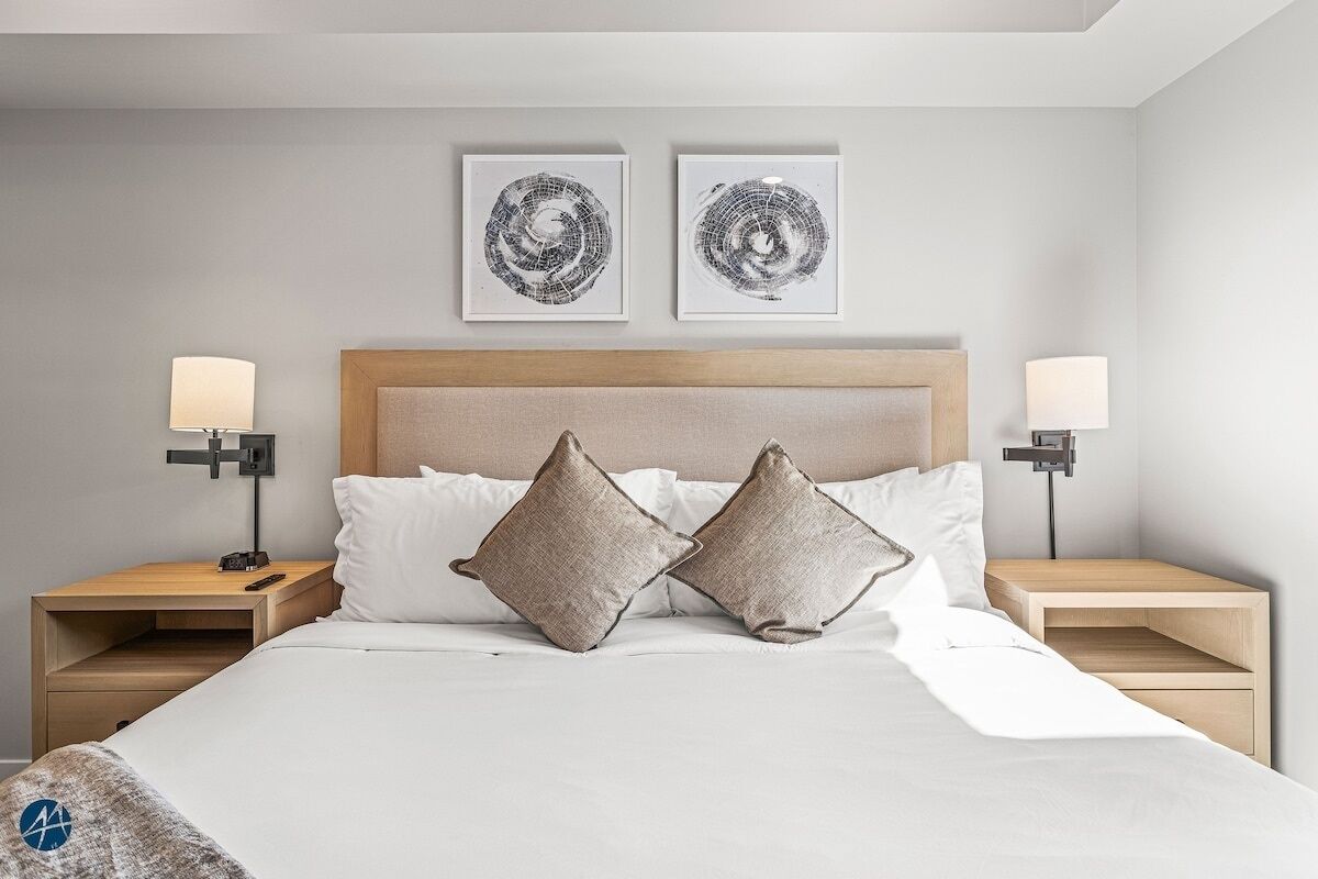 Een moderne hotelkamer met een groot bed, twee nachtkastjes en twee wandlampen.