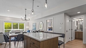 A modern kitchen with a central island, wooden cabinets, and a dining area with a table and chairs. - 2 Bed/2 Bath Sparrowhawk Resort-Sleeps 6 (Dead Man's Flats)