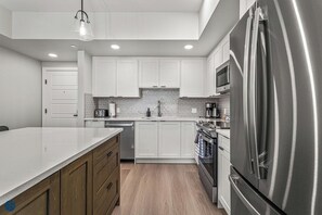 Una cocina moderna con armarios blancos, electrodomésticos de acero inoxidable y piso de madera.