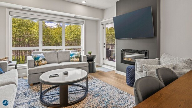 A modern living room with a large window, a flat-screen TV, and a fireplace. - The Westview - 2 Bed/2Bath Sleeps 6 (Dead Man's Flats)