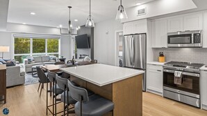 A modern kitchen with white cabinets, stainless steel appliances, and a central island with bar stools. - The Westview - 2 Bed/2Bath Sleeps 6 (Dead Man's Flats)