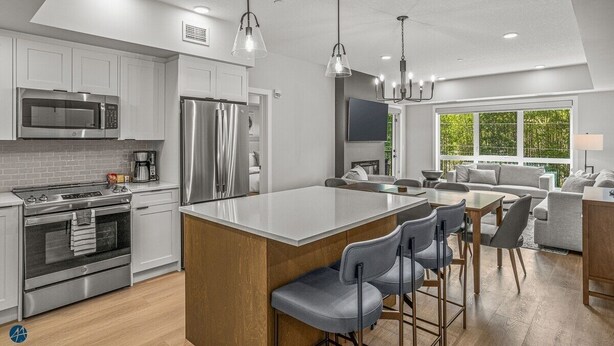 A modern kitchen with stainless steel appliances, a central island with bar stools, and a dining area with a sofa and coffee table. - 2 Bed/2 Bath Sparrowhawk Resort-Sleeps 6 (Dead Man's Flats)