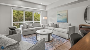 A modern living room with a sectional sofa, a round coffee table, and a large window with a view of trees. - 2 Bed/2 Bath Sparrowhawk Resort-Sleeps 6 (Dead Man's Flats)