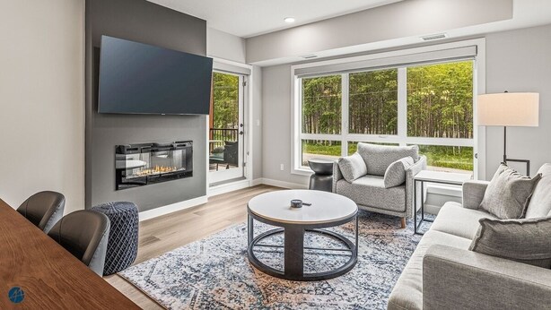 A modern living room with a fireplace, large windows, and a round coffee table.