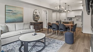A modern living room with a sofa, coffee table, and dining area with chairs.