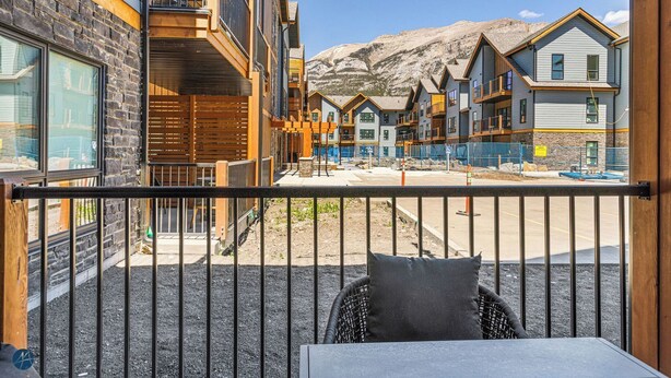 A balcony with a view of a mountain, a building with a wooden facade, and a construction site in the background.