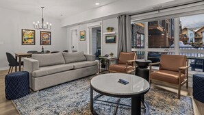 A modern living room with a sofa, armchairs, a coffee table, and a dining area.