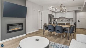 Una cocina moderna con armarios blancos, un comedor con mesa redonda y una chimenea.
