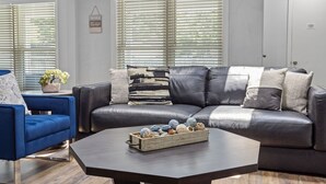 Un salon avec un canapé en cuir foncé, un fauteuil bleu et une table basse agrémentée d’objets décoratifs.