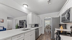 Une cuisine moderne avec des meubles blancs, un lave-vaisselle, une cuisinière et un four à micro-ondes.