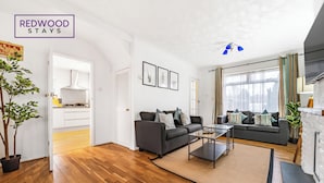 Een moderne woonkamer met houten vloeren, twee banken, een salontafel en een open haard.