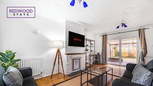 Een moderne woonkamer met een open haard, een televisie en uitzicht op buiten.
