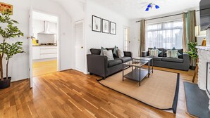 Uma sala de estar moderna com piso de madeira, dois sofás, uma mesa de centro e uma lareira.