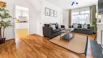 A modern living room with hardwood flooring, two sofas, a coffee table, and a fireplace.