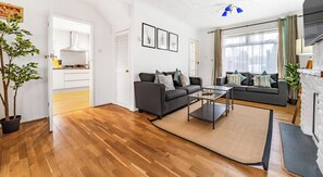 Una sala de estar moderna con suelo de madera, dos sofás, una mesa de centro y una chimenea.