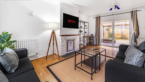 Uma sala de estar moderna com lareira, televisão e vista para o exterior.