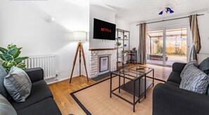Una sala de estar moderna con chimenea, televisor y vistas al exterior.