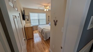 Un dormitorio con cama, ventilador de techo y ventana con persianas.