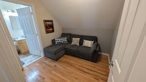 Una habitación con un sofá seccional gris, un cuadro y suelo de madera.
