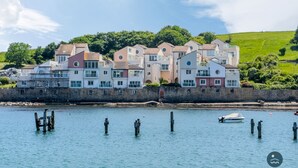 A waterfront property with multiple buildings, a stone wall, and a clear view of the water. - Pebbles - The Haven, Swanage (Swanage)
