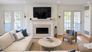 Una sala de estar con chimenea, televisor, sofá, mesa de centro y una silla.