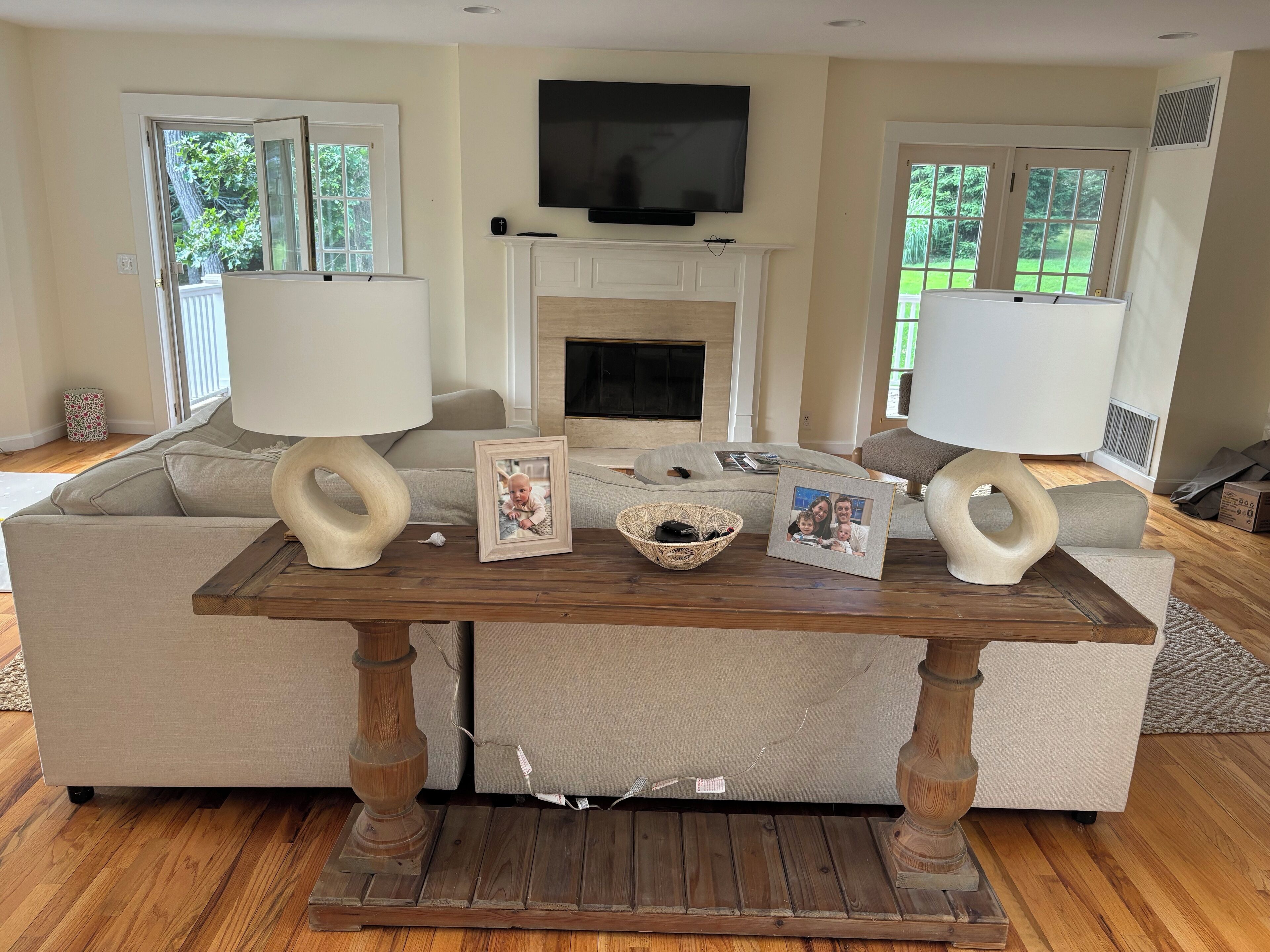 A living room with a fireplace, a television, and a wooden coffee table with picture frames and a basket.