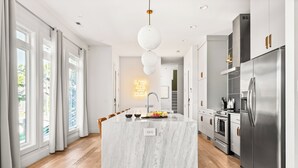 A modern kitchen with a marble island, stainless steel appliances, and a pendant light. - 3-Level Lux Home! Rooftop! Firepit! 6 min to DT! (Nashville)