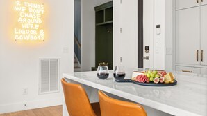 A modern kitchen with a marble countertop, two wine glasses, and a fruit platter. - 3-Level Lux Home! Rooftop! Firepit! 6 min to DT! (Nashville)