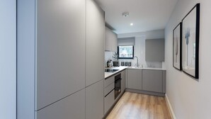 Eine moderne Küche mit grauen Schränken, Holzboden und einem Fenster, das für natürliches Licht sorgt.
