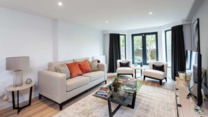 Una sala de estar moderna con un sofá, sillones, una mesa de centro y un mueble para la televisión.