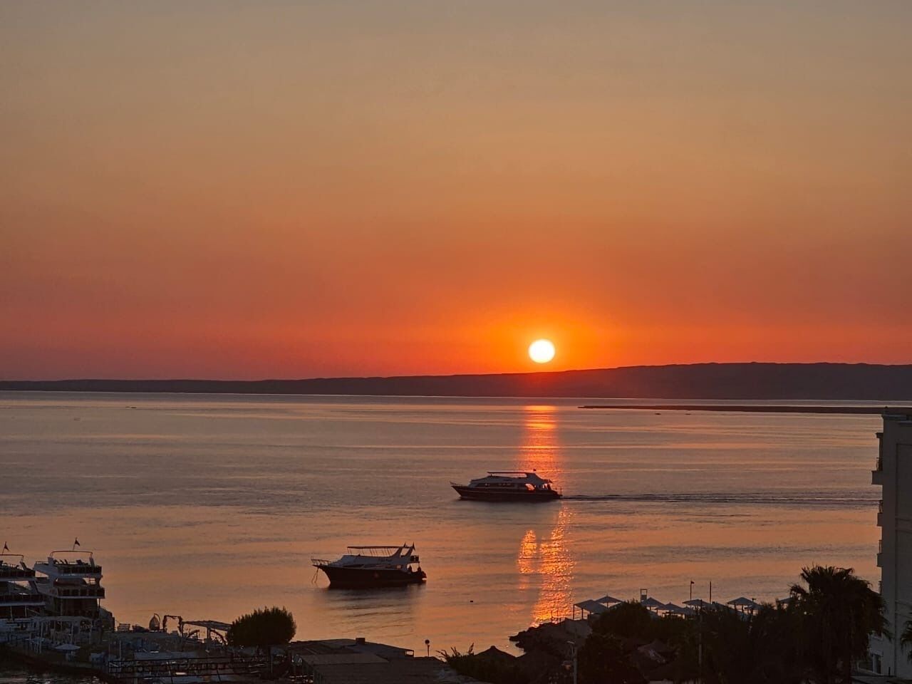 A sunset over a calm sea with boats.
