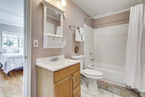 Ein Badezimmer mit einem Holzbadschränken, Toilette, Badewanne und Duschvorhang.